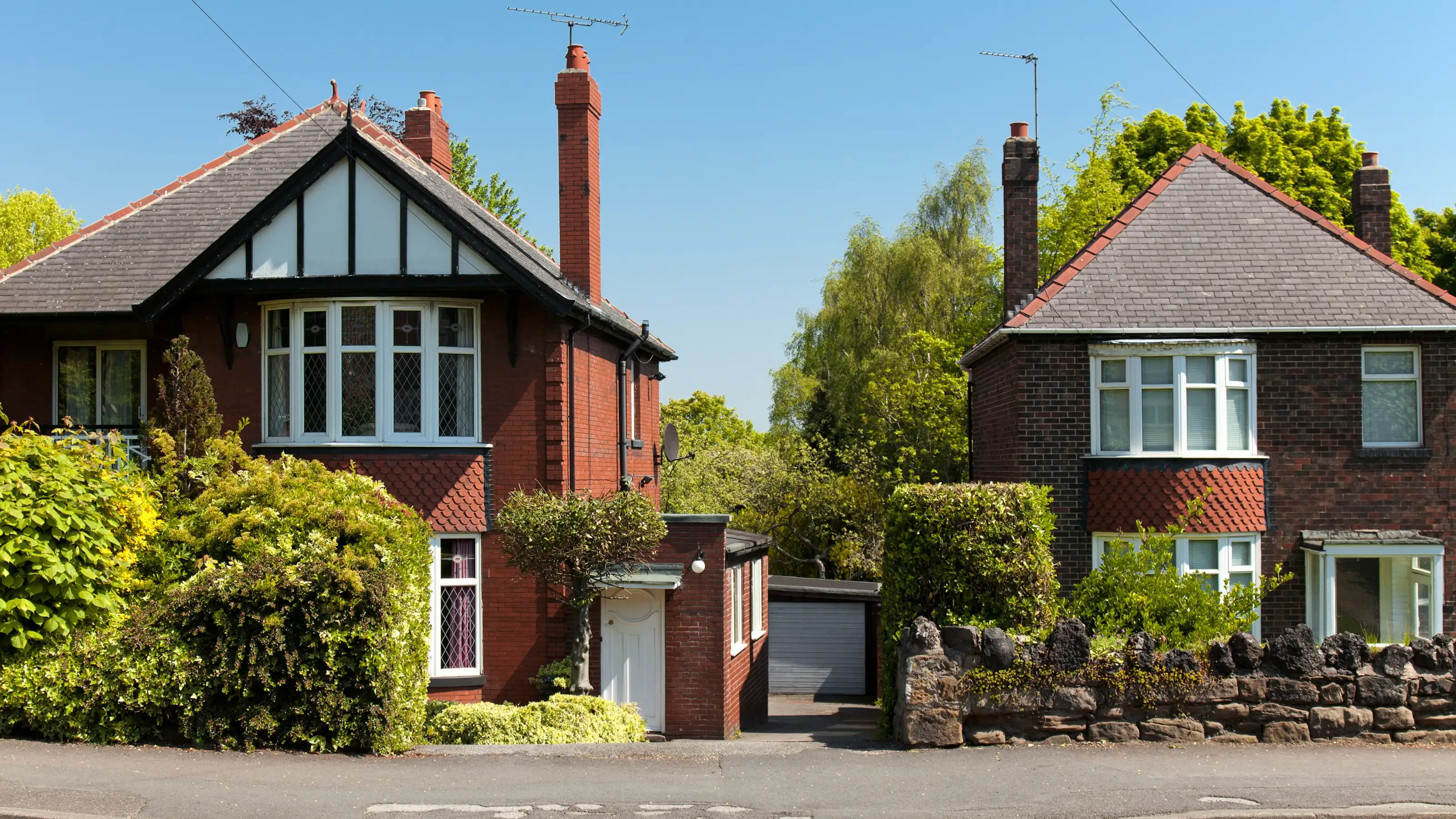 Classic detached brick houses on a leafy UK street, the kind of everyday properties Straight Up Stays manages